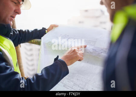 Engineers discussing blueprints at construction site Stock Photo