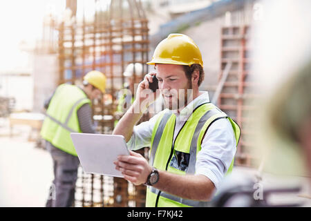 Engineer with digital tablet talking on cell phone at construction site Stock Photo