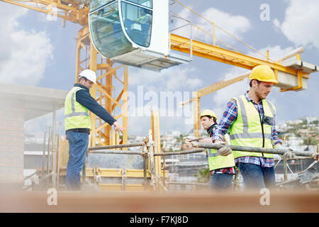 Foreman guiding construction workers below crane at construction site Stock Photo