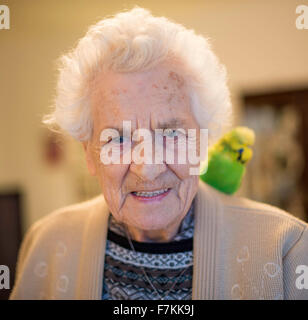 An elderly lady in a care home with a pet budgie on her shoulder Stock Photo