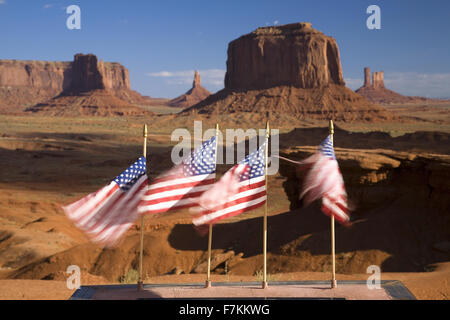 US Flags blowing in wind in front of red buttes and colorful spires of Monument Valley Navajo Tribal Park, Southern Utah near Arizona border Stock Photo