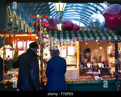 The Apple Market Hall and Christmas shoppers at Covent Garden market stall with Christmas decorations London UK Stock Photo