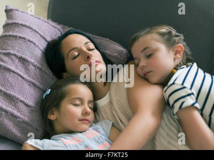 Serene mother and daughters napping on sofa Stock Photo