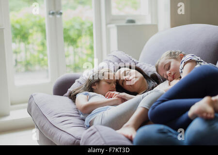 Serene mother and daughters napping on living room sofa Stock Photo