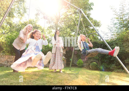 Carefree multi-generation women swinging in backyard Stock Photo
