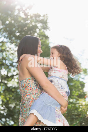 Affectionate mother holding and hugging daughter outdoors Stock Photo