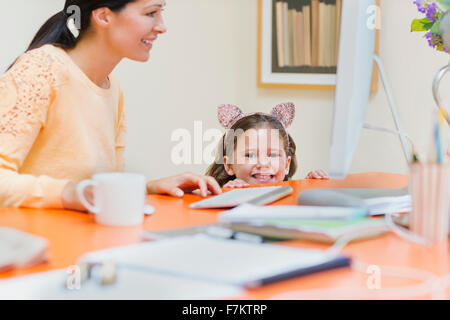 Portrait smiling girl in mouse ears headband with mother at computer Stock Photo