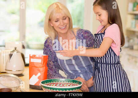 Grandmother and granddaughter baking sifting flour in kitchen Stock Photo