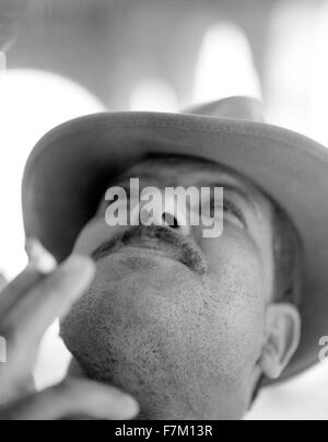 A close up portrait of a local Tunisian man wearing a hat and smoking a cigarette. Tozeur, Tunisia, North Africa Stock Photo