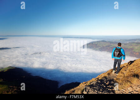 Man hiking above foggy valley from near summit of Mount Rigi, Bänderenweg route, Switzerland, Europe Stock Photo