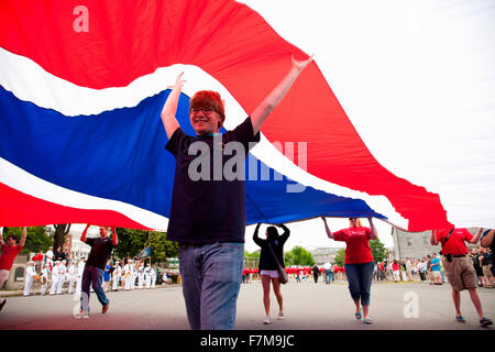 Boy stands underneath British Flag for Bicentennial of War of 1812 which also feaures Canadian and British flag, USS Constitution Ship and Museum, Freedom Trail, Boston, MA Stock Photo