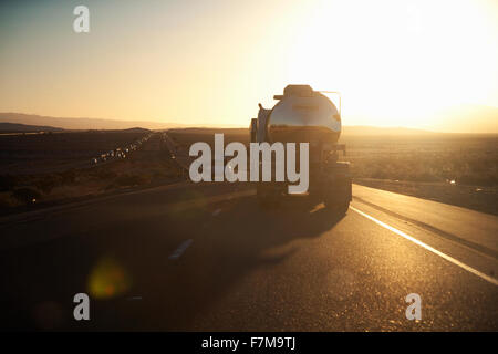 Fuel truck drives into setting sun on Interstate 15 in California Stock Photo