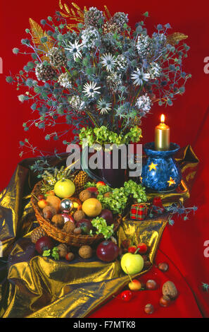 Festive New Year's, Christmas still life with a winter bouquet of flowers, a candlestick with a candle and fruit with nuts. Stock Photo