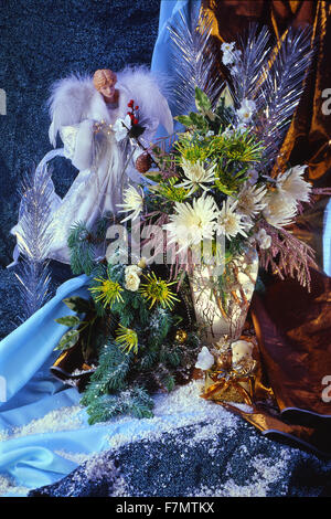 Festive New Year's, Christmas still life in blue tones a sbely angel and a bouquet of winter flowers of chrysanthemums. vertical Stock Photo