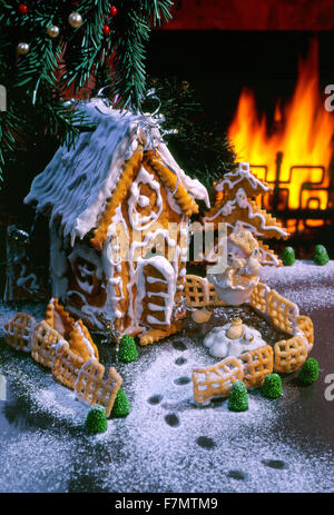 Festive New Year's, Christmas still life with a gingerbread lodge and a bear cub toy against fire in a fireplace. vertical. Stock Photo