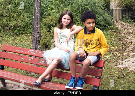 Girl and boy hanging out together on park bench Stock Photo