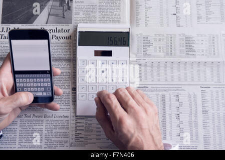 Investor using smartphone and calculator Stock Photo