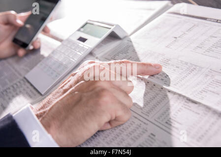 Checking stock market performance in newspaper Stock Photo