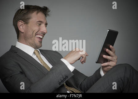 Man laughing while using digital tablet Stock Photo