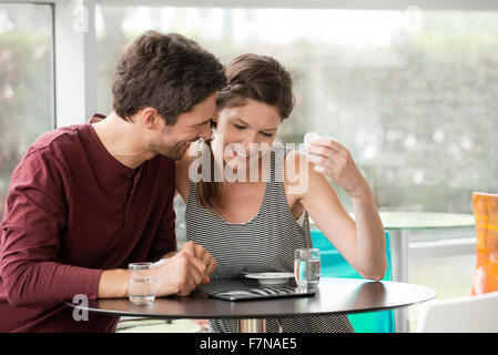 Couple in cafe watching video streaming on digital tablet Stock Photo