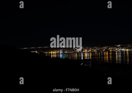 tromsoe city island at night with the bridge connecting the island to the mainland with strong light reflection on fjord water Stock Photo