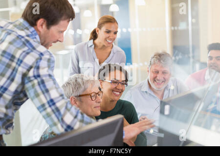 Smiling students at computer in adult education classroom Stock Photo