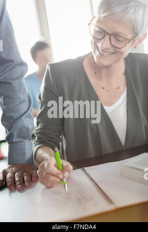 Senior woman reviewing homework in adult education classroom Stock Photo
