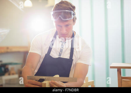 Carpenter measuring wood with ruler in workshop Stock Photo