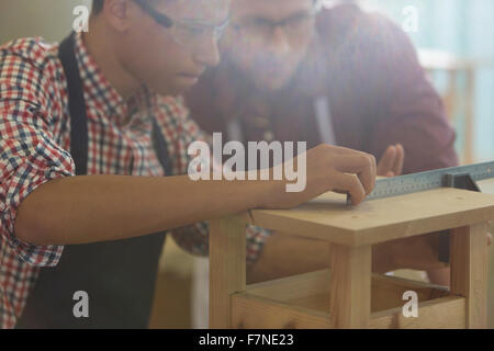 Focused carpenters measuring wood with ruler in workshop Stock Photo