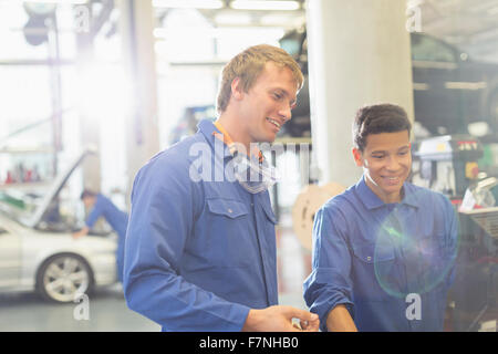 Smiling mechanics using computer in auto repair shop Stock Photo