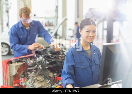 Portrait smiling female mechanic at computer in auto repair shop Stock Photo