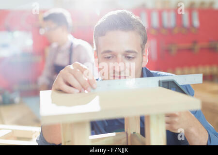 Carpenter measuring wood with ruler in workshop Stock Photo