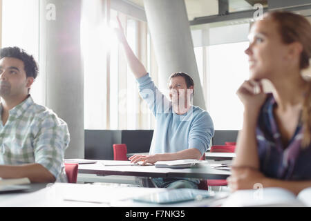 Eager man raising hand in adult education classroom Stock Photo