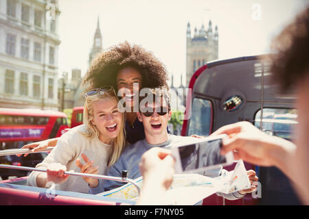 Enthusiastic friends being photographed on double-decker bus Stock Photo