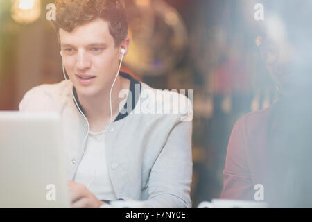 Man listening to music on headphones and using laptop Stock Photo