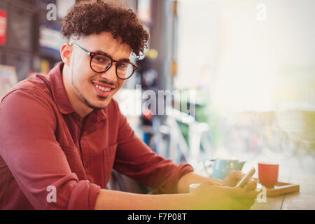 Portrait smiling man with curly black hair texting in cafe Stock Photo
