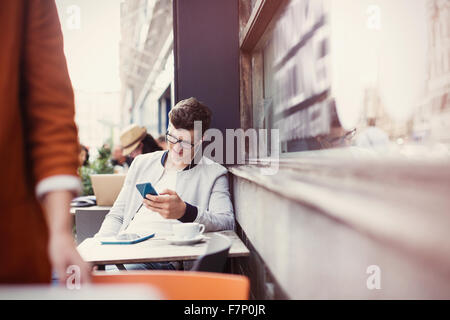 Man listening to headphones with mp3 player at sidewalk cafe Stock Photo