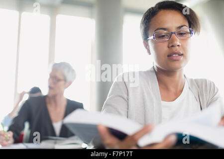 Serious woman reading book in adult education classroom Stock Photo