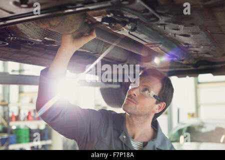 Mechanic working under car in auto repair shop Stock Photo