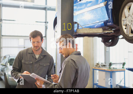 Mechanics reviewing paperwork in auto repair shop Stock Photo