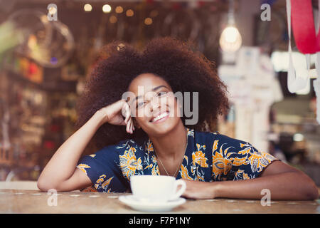 Portrait smiling woman with afro drinking coffee in cafe Stock Photo
