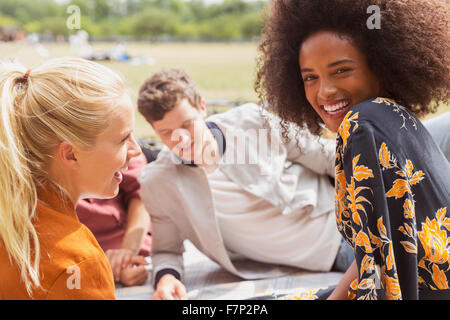 Portrait smiling woman hanging out with friends in sunny park Stock Photo