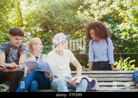 College students hanging out studying on park bench Stock Photo