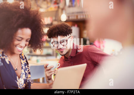 Friends using laptop and drinking coffee in cafe Stock Photo