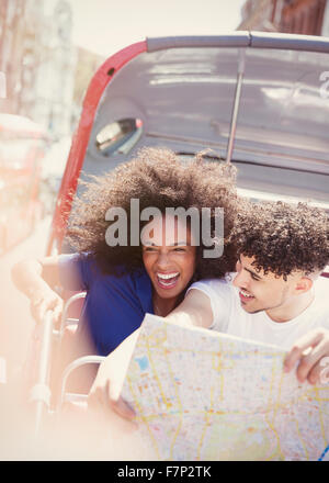 Enthusiastic couple with map on double-decker bus Stock Photo