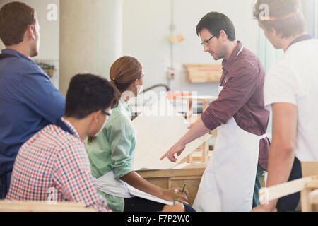 Carpentry teacher explaining blueprints to students in workshop Stock Photo