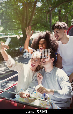 Enthusiastic friends taking selfie on double-decker bus Stock Photo