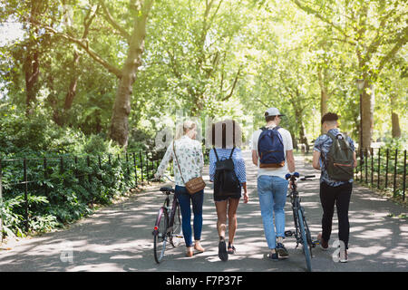 Friends walking with bicycles in park Stock Photo