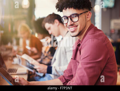 Portrait smiling man with curly black hair using digital tablet in cafe Stock Photo
