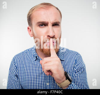 Portrait of a young casual man showing finger over lips isolated on a white background Stock Photo